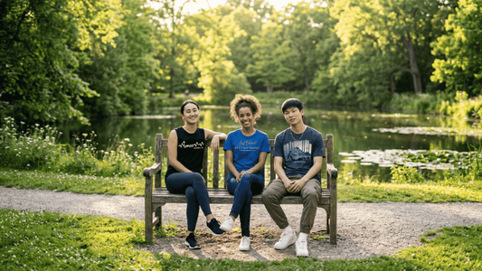 Three friends sitting together on a park bench in Fort Worth, Texas, wearing Christian apparel including a black Galatians 2:20 tank top and blue t-shirts with Bible verses.