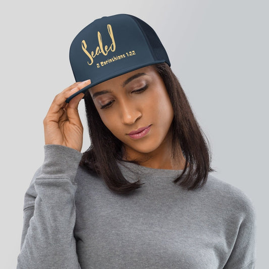 Woman wearing a navy blue trucker hat with gold text Sealed 2 Corinthians 1:22