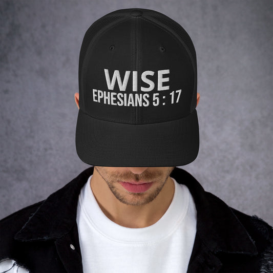 Person wearing Truth Matters’ Ephesians 5:17 Trucker Cap with ‘WISE’ embroidery on black mesh cap.